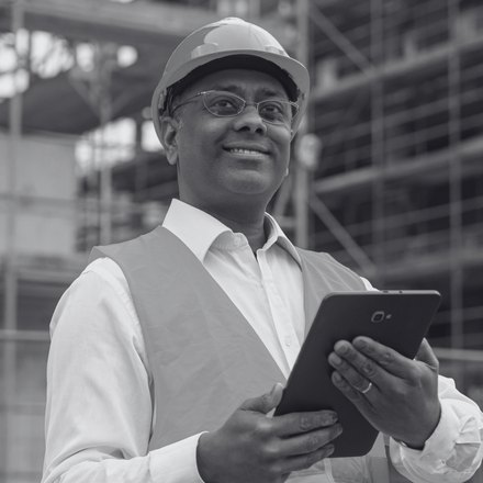 A commercial operator with a hard hat and tablet at a construction site