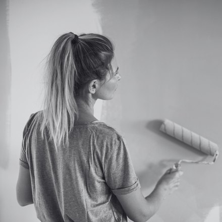 A homeowner painting an interior wall with a roller
