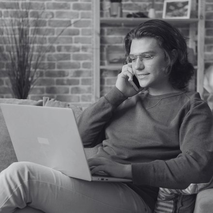 A property owner on a laptop and phone at home, following a project remotely